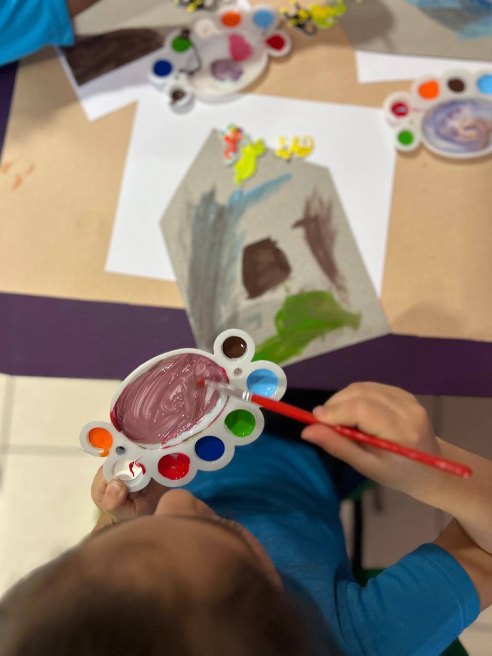 Niña pintando con paleta de colores durante un taller de arte de Rincón de Historias